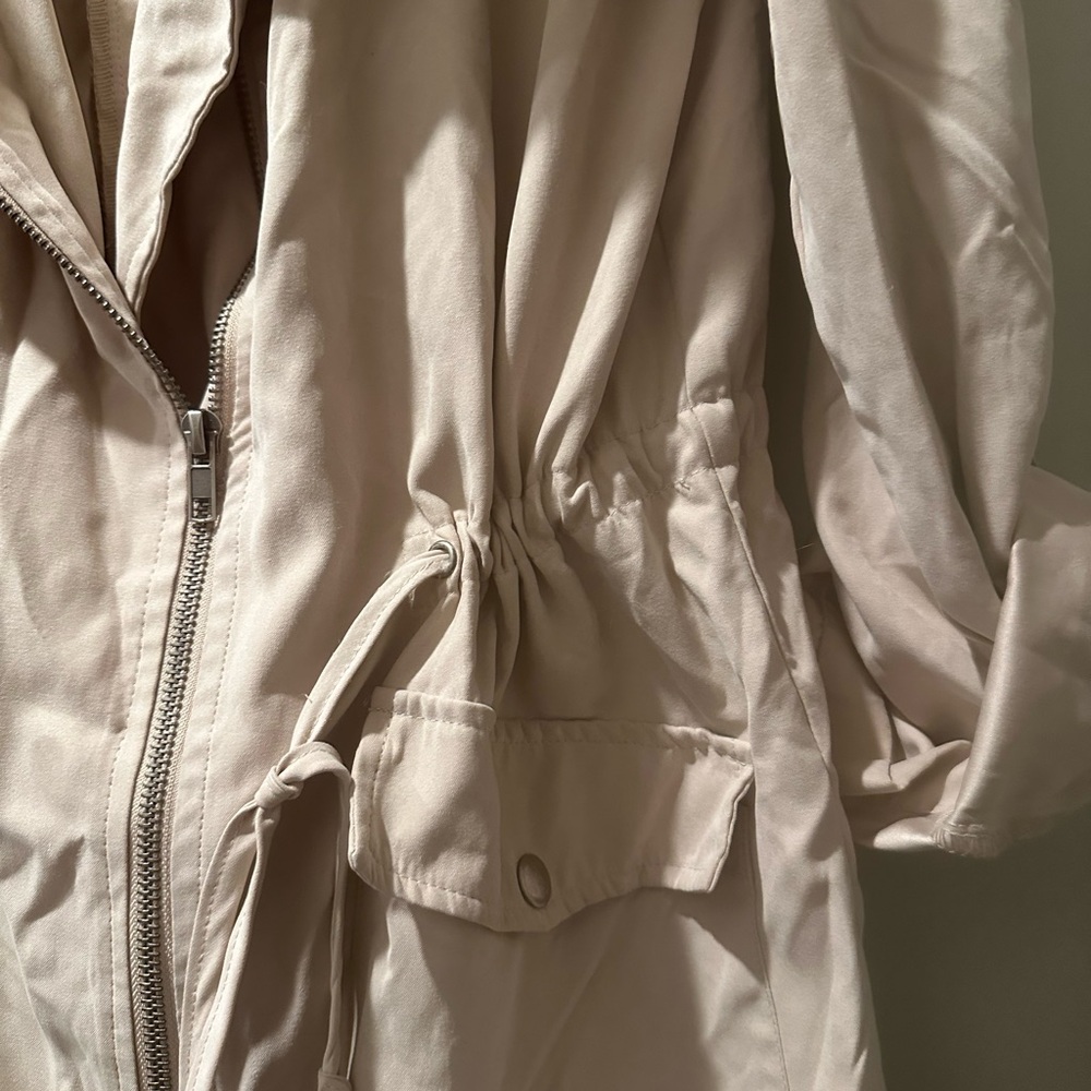 Rain coat beige ties tight in the middle to cinch off waist.